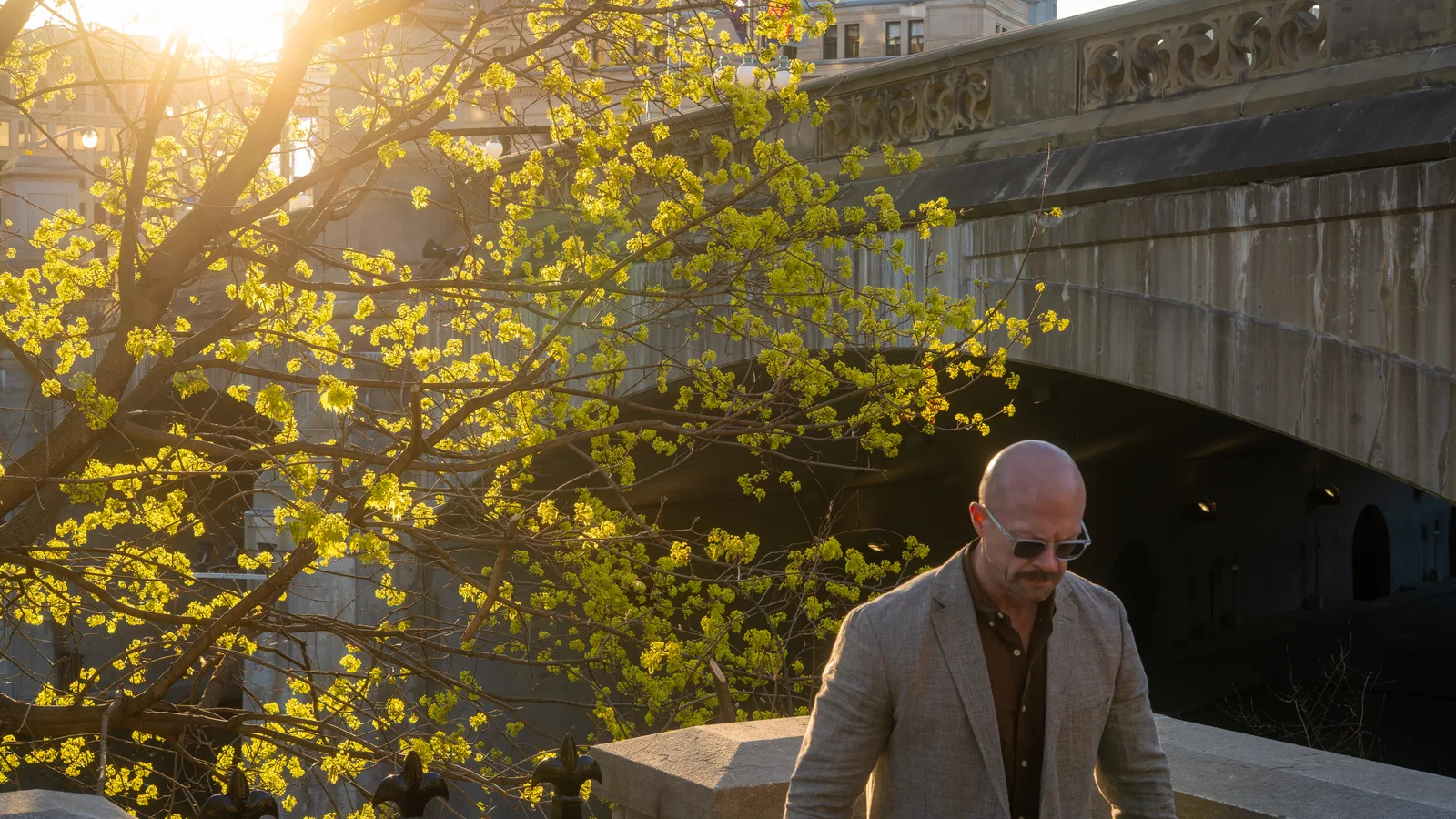 Tyson DesMarais walking a bridge at golden hour, the city behind him.