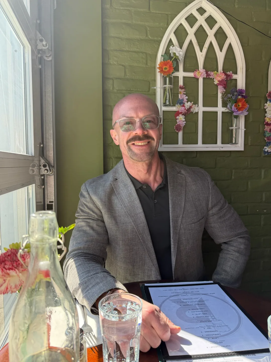 Tyson at a café table, smiling, mid-conversation.
