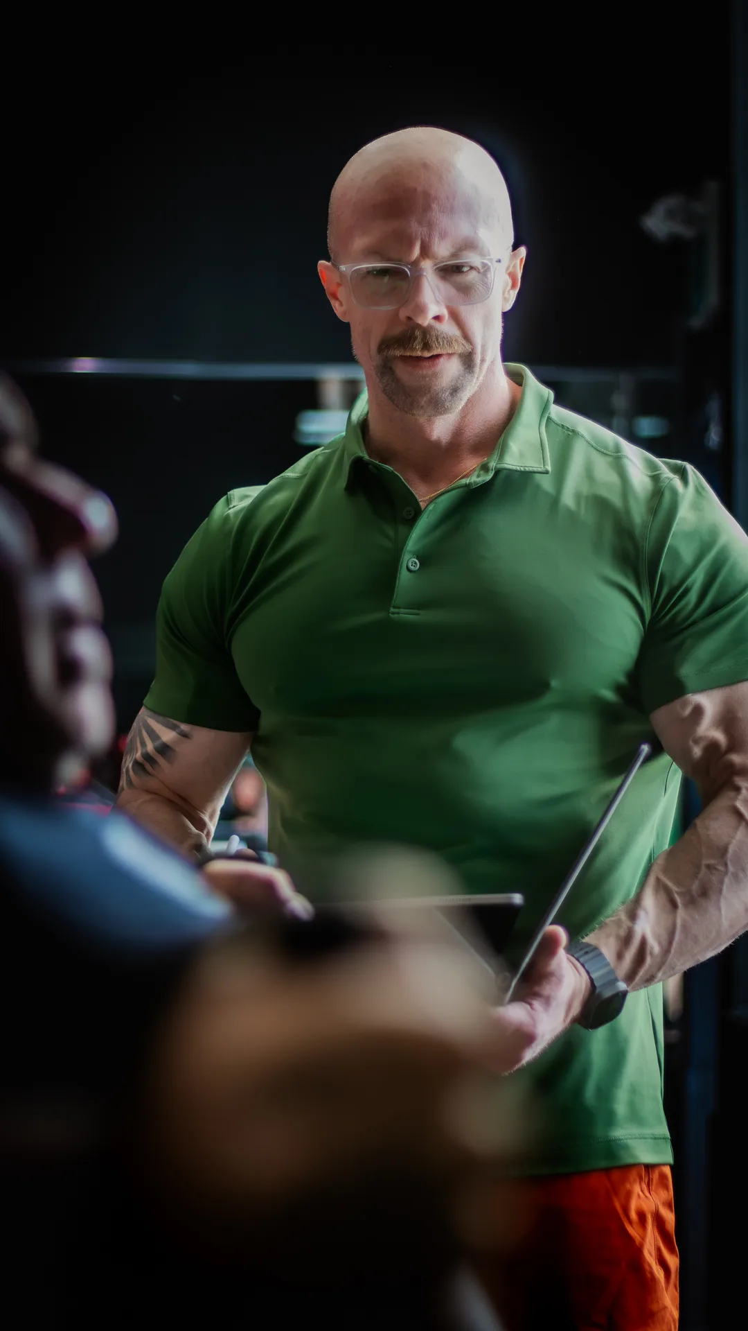 Tyson mid-session at the gym, tablet in hand, eyes on the client in front of him