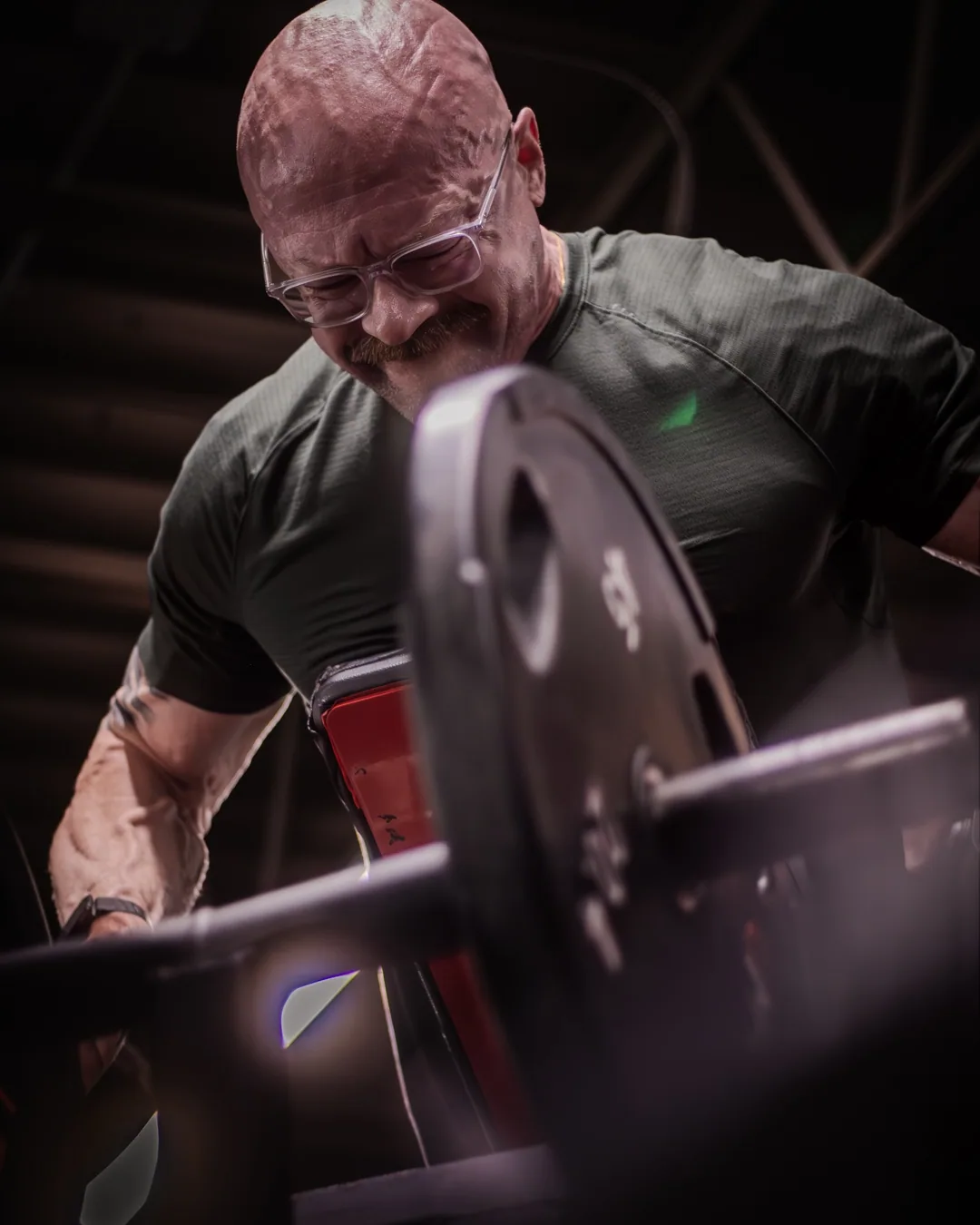 Tyson head down under a loaded barbell, teeth set, in a dark gym