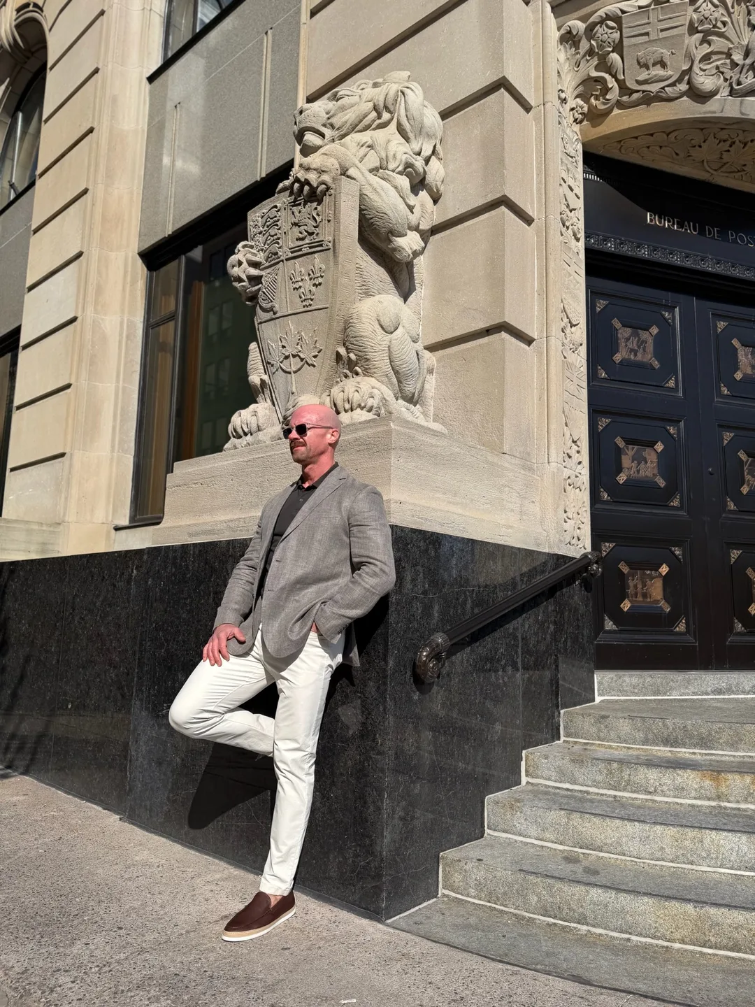 Tyson DesMarais leaning against the stone plinth of a heritage building, a carved lion above him