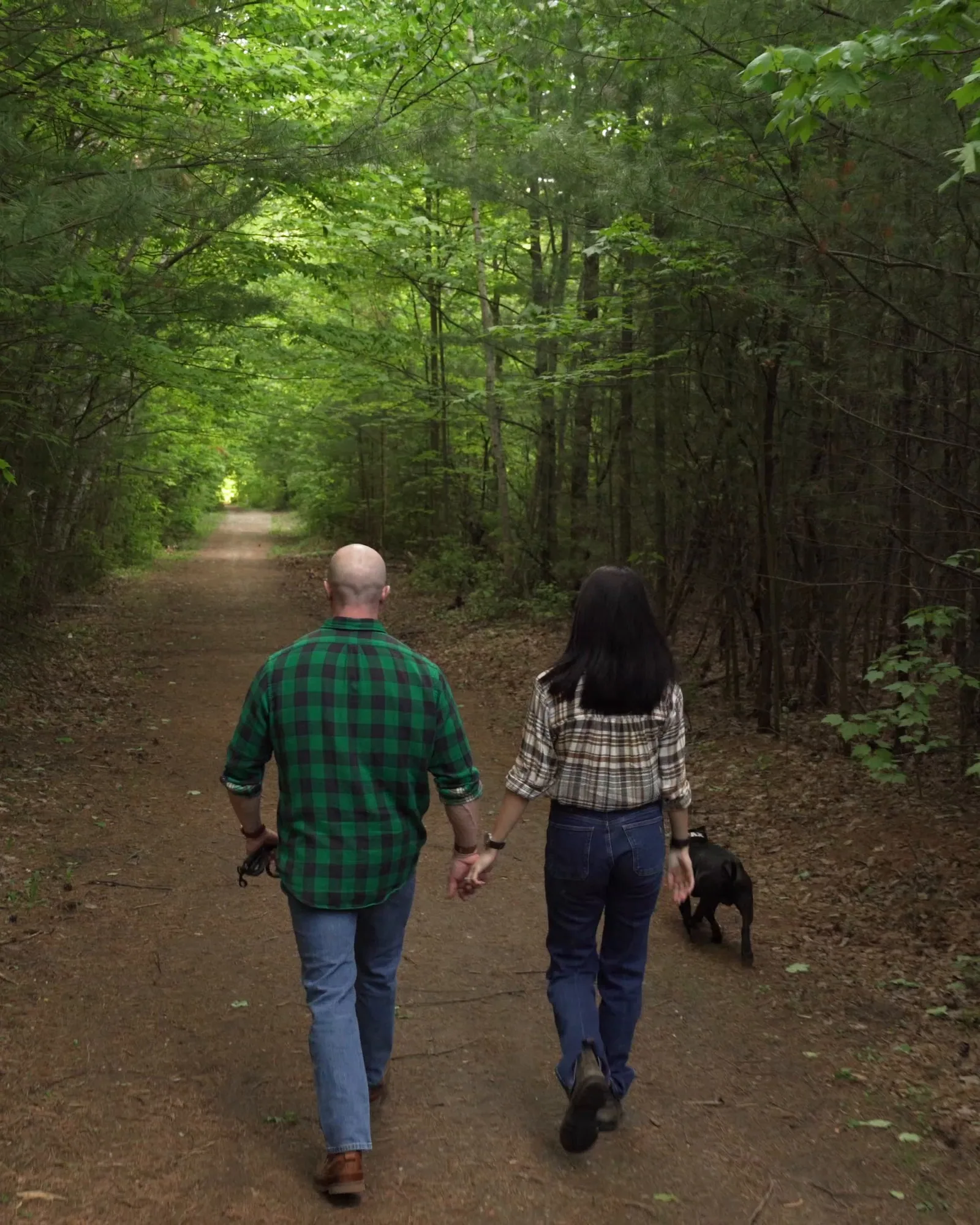 Tyson and his wife walking away hand in hand down a forest path, their dog beside her