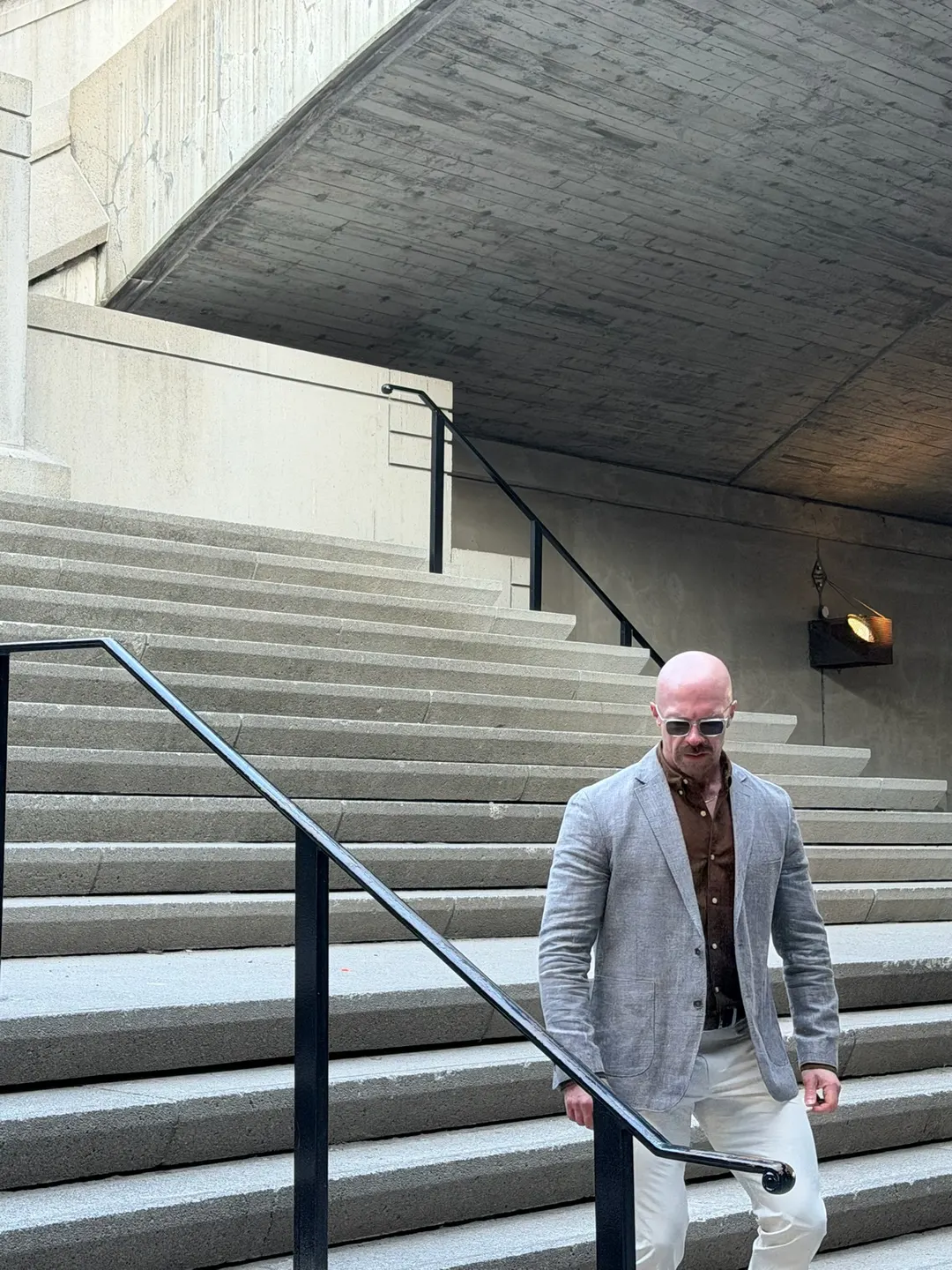 Tyson DesMarais walking down a flight of stone steps in a linen jacket