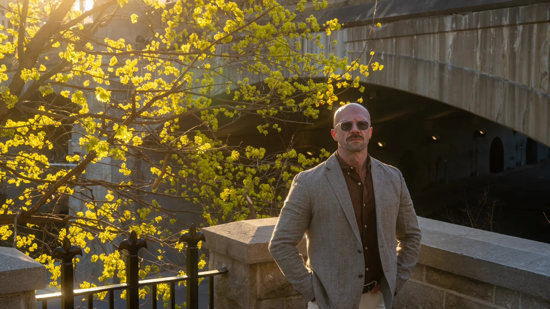 Tyson DesMarais leaning on a stone railing, looking straight at you