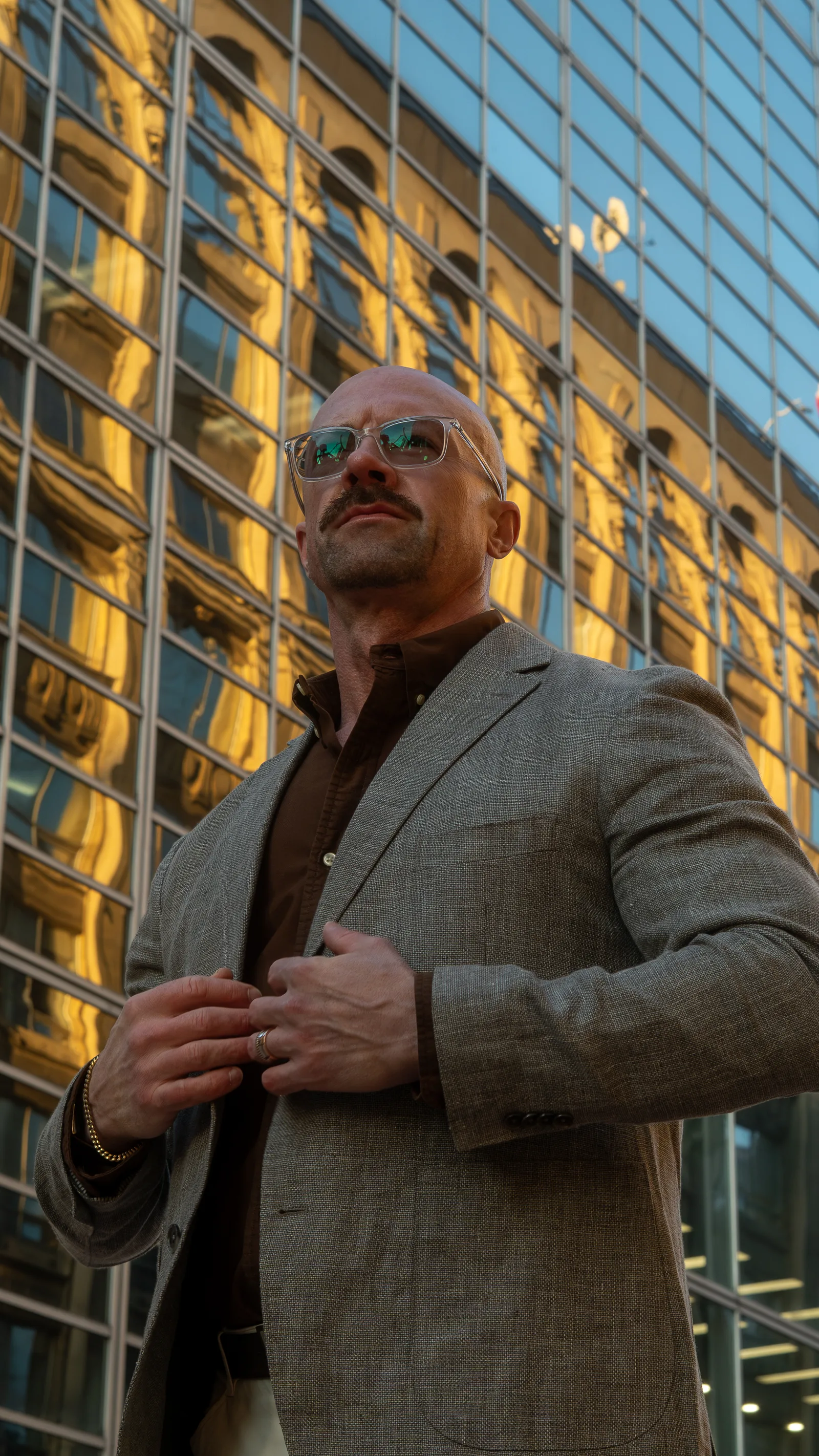 Tyson DesMarais in a blazer in front of a downtown Ottawa glass tower, fastening his jacket.